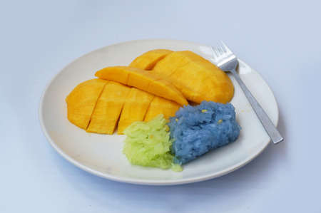 Asia - Asian eating food, Thai dessert, Sticky rice in coconut cream with sweet ripe mango, with fork on white plate isolated on white background, close upの写真素材