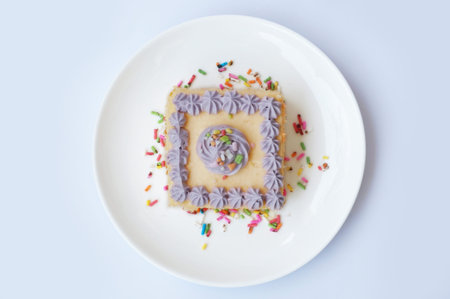 Colorful cream butter cake decorated with sugar topping on white plate isolated on white background