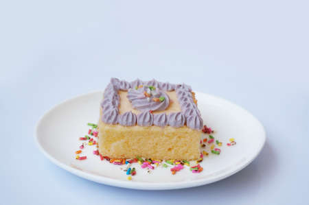 Colorful cream butter cake decorated with sugar topping on white plate isolated on white backgroundの写真素材