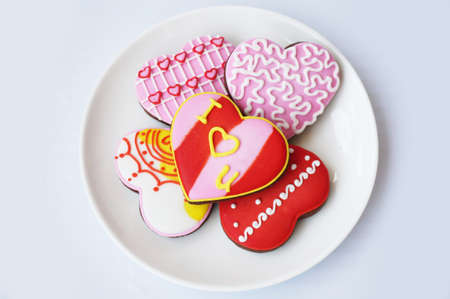 Love Heart Cookies: Chocolate cookies decorated with various color of sugar topping on white plate isolated on white background.の写真素材