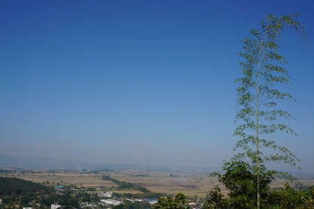 A photo of landscape of village in the valley and trees with beautiful blue sky in natural background of a winter day at Chiang Rai province, northern of Thailandの写真素材