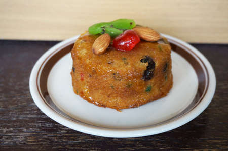 A photo of colorful fruit cake decorated with almond, kiwi and cherry on wooden background, close upの写真素材