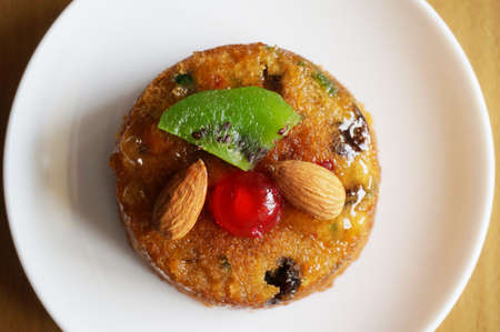 A photo of colorful fruit cake decorated with almond, kiwi and cherry on wooden background, close upの写真素材