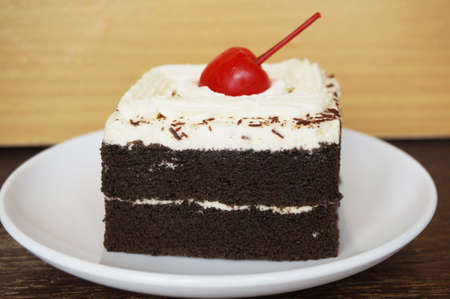 Colorful chocolate black forest cake decorated with cherry on wooden background, close upの写真素材
