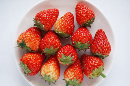 Close up of photo of very fresh harvested strawberries on white plate isolated on white backgroundの写真素材