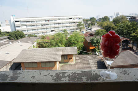 A photo of maraschino cherries in champagne glass on balcony of an old building with natural backgroundの写真素材