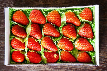 Close up of photo of very fresh harvested strawberries in box on wooden backgroundの写真素材