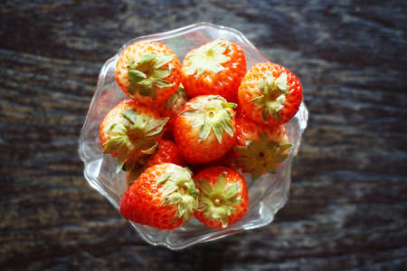 Close up of photo of very fresh harvested strawberries on glass blow on wooden backgroundの写真素材