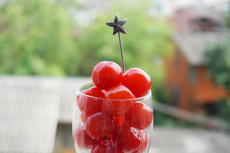 A photo of maraschino cherries in champagne glass on balcony of an old building with natural background, close upの写真素材