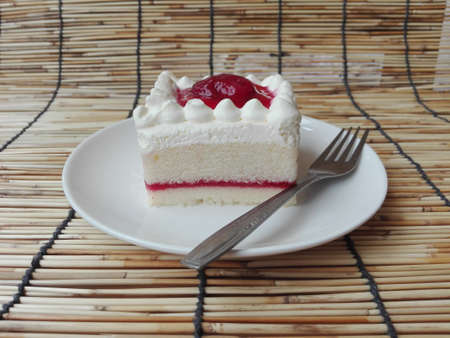 A photo of colorful cream vanilla layer cake decorated with strawberry jam on rattan curtain background, close upの写真素材