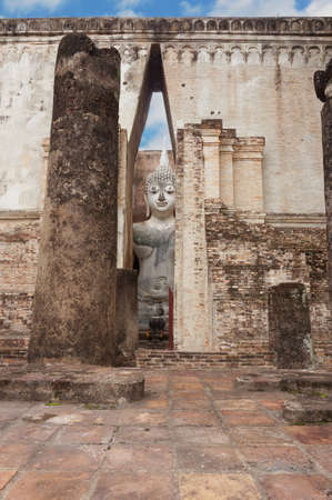 A photo of Buddha Sitting against the wall under the cloudy sky, is a World Heritage at Wat Sri Chum temple, Sukhothai, Thailandの写真素材