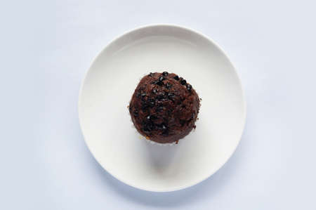 A photo of colorful brown chocolate muffin on white plate isolated on white backgroundの写真素材