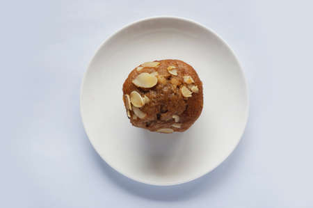 A photo of colorful brown almond muffin on white platel isolated on white background, close upの写真素材