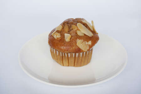 A photo of colorful brown almond muffin on white plate isolated on white background, close upの写真素材