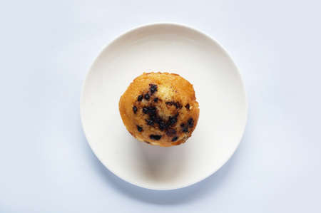 A photo of colorful butter muffin decorated with chocolate topping on white plate isolated on white background, close upの写真素材