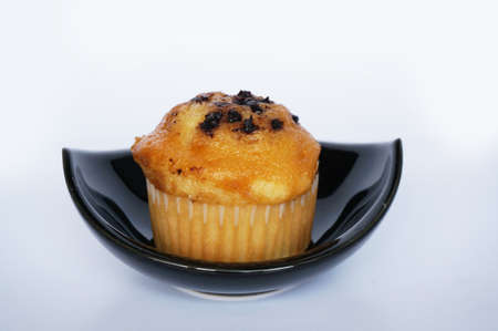 A photo of colorful butter muffin decorated with chocolate topping on black bowl isolated on white background, close upの写真素材