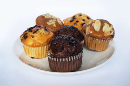 A photo of colorful brown chocolate, almond and butter muffin on white plate isolated on white backgroundの写真素材