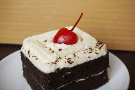 Colorful chocolate black forest cake decorated with cherry on wooden background, close upの写真素材