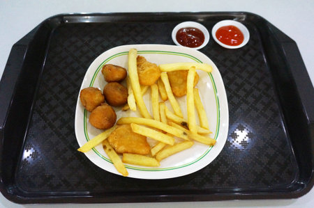 A photo of Chicken and Pork Nuggets with French Fries on tray isolate on white background, close up