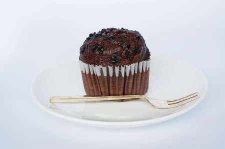 A photo of colorful brown chocolate muffin on white plate isolated on white backgroundの写真素材