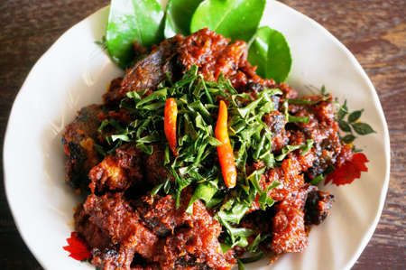 Asia - Asian food, Thaifood, phad phed pla duk thod krob: Stir-Fried Catfish fishes in spicy curry sauce on white plate on wooden background, closeupの写真素材