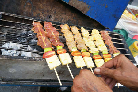 A photo of hands making grilled chicken and pork barcebue, close upの写真素材