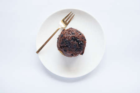 A photo of colorful brown chocolate muffin on white plate isolated on white backgroundの写真素材