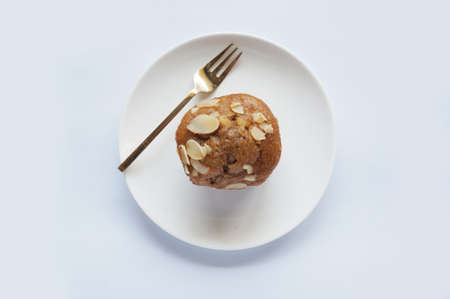 A photo of colorful brown almond muffin on white plate isolated on white backgroundの写真素材