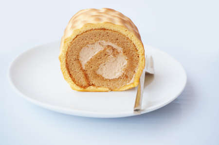 Colorful cream butter and coffee cake roll on white plate isolated on white backgroundの写真素材