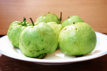 Close up of photo of very fresh green common guava (Psidium guajava) on white plate of wooden backgroundの写真素材