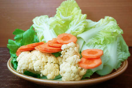 Vegatables set - diet food for health: green sweet basil (Thai basil), Celery (Smallage), morning glory, cauliflower, Chinese cabbages and orange carrots on plate on wooden backgroundの写真素材