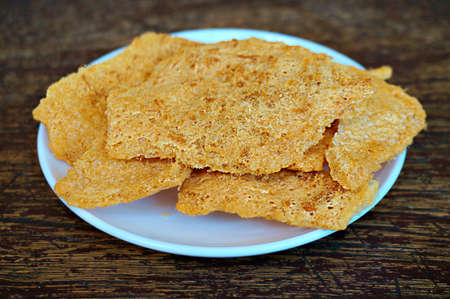 Asia-Asian, Thai food: a photo of Dried shredded flossy pork Rice cracker on white plate on wooden background, close upの写真素材