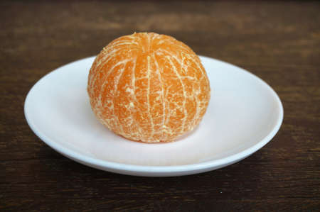 Close up of photo of very fresh peeled orange on white plate on wood table backgroundの写真素材