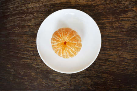 Close up of photo of very fresh peeled orange on white plate on wood table backgroundの写真素材