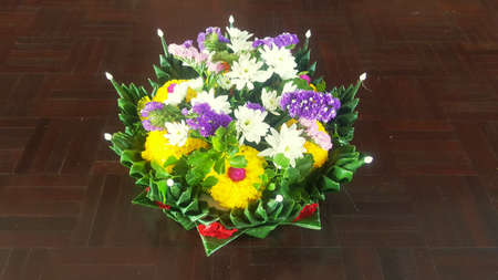 A photo of giant Krathong art work at the Loy Krathong Festival day of Thailand, made of green banana leaves and flowers (Chrysanthemum, Marigold, etc) on wooden background, close upの写真素材