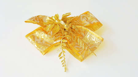 A photo of decorative golden silk bows with horizontal gold ribbons, for decoration, promotion, advetrisment, sale or celebration on chirstmas, new year, valentine, birthday, wedding anniversary, isolated on white background, close upの写真素材