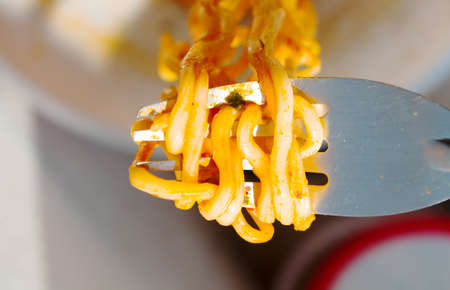yellow Instant noodles on a spoon and fork.の写真素材