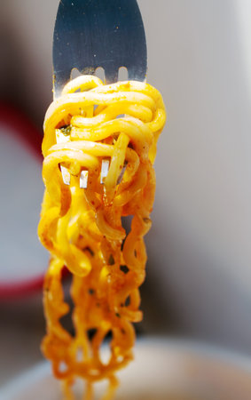 yellow Instant noodles on a spoon and fork.
