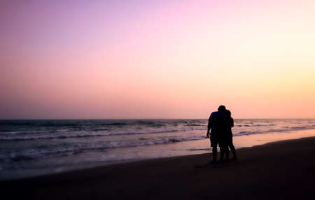 silhouette of couples hugging on the beach on the beach with sunrise in the sea for valentine's dayの写真素材