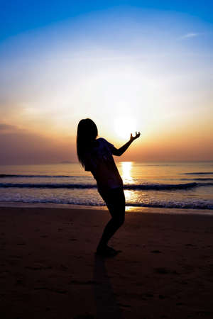 silhouette of woman alone and wave on the beach with sunset in the seaの写真素材
