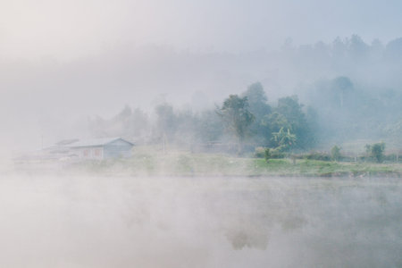 Cottage in the village among mountain and fogの写真素材