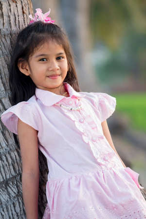 Girl leaning against a coconut tree の写真素材