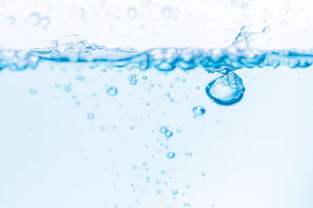 Surface of the blue water waves splash on a white backgroundの写真素材