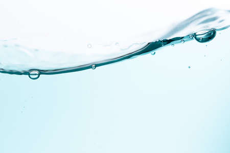 Surface of the blue water waves splash on a white backgroundの写真素材