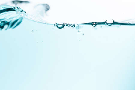 Surface of the blue water waves splash on a white backgroundの写真素材