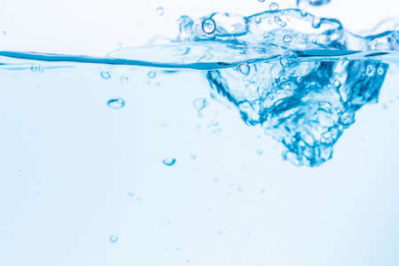Surface of the blue water waves splash on a white backgroundの写真素材