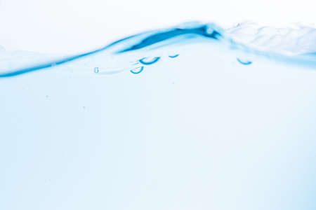 Surface of the blue water waves splash on a white backgroundの写真素材
