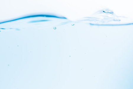 Surface of the blue water waves splash on a white backgroundの写真素材