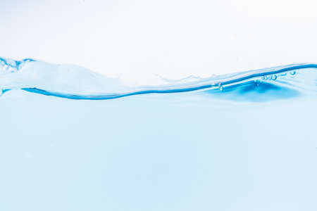 Surface of the blue water waves splash on a white backgroundの写真素材