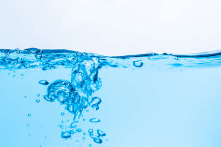 Surface of the blue water waves splash on a white backgroundの写真素材